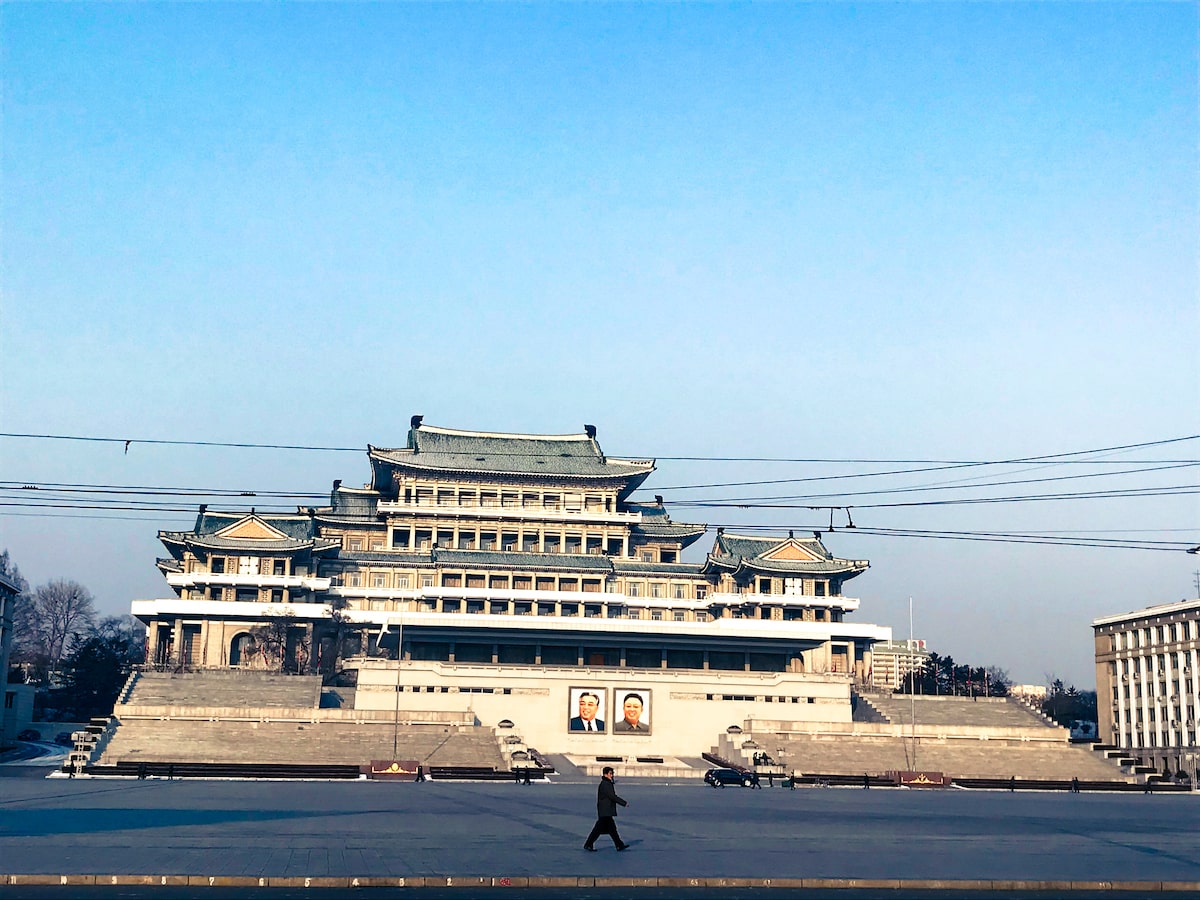 A local man walks past large photos of former North Korean leaders in a barren Kim Il-sung Square