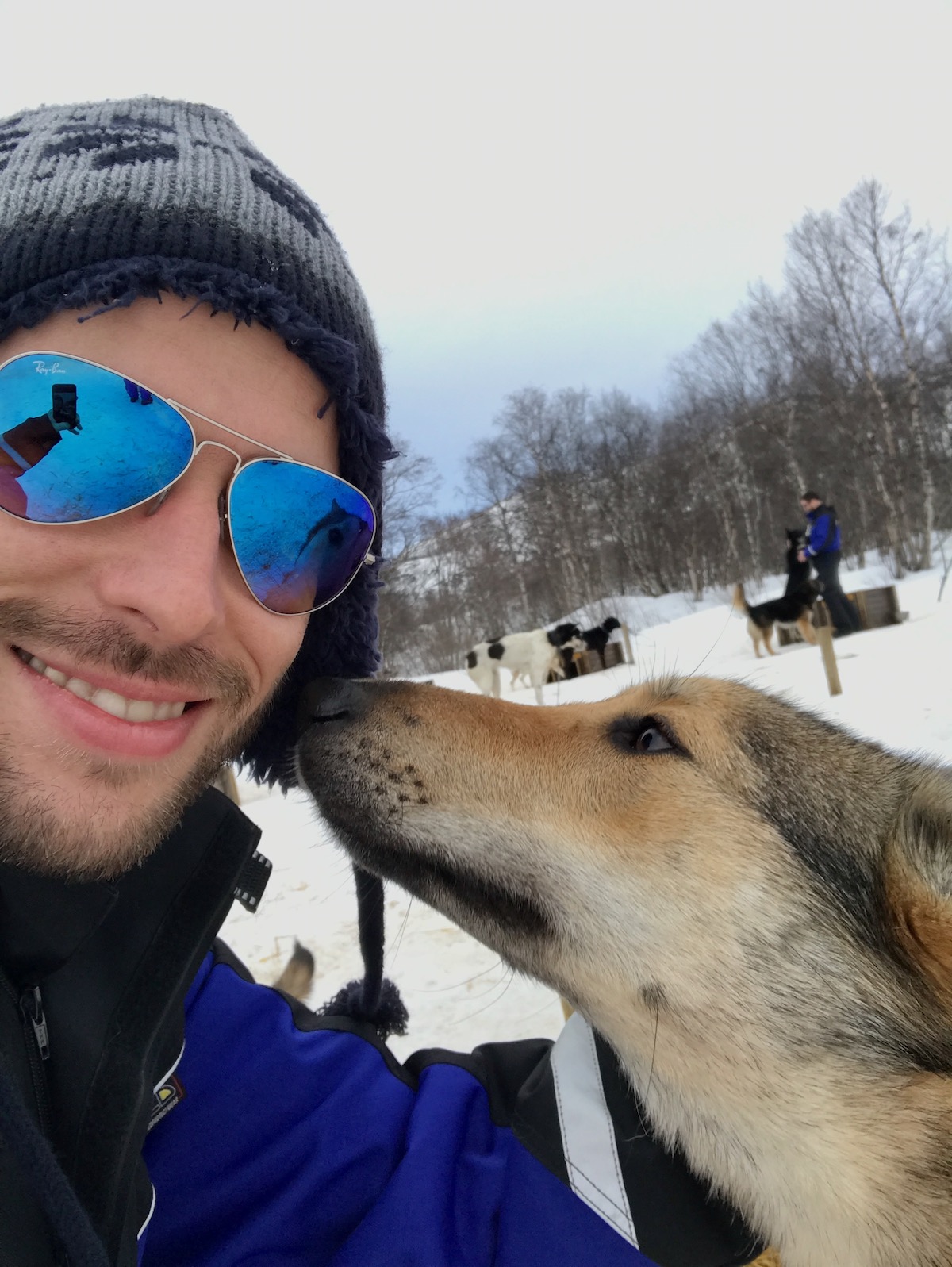 A dog sniffs a man's face in the Arctic Cicle of Norway