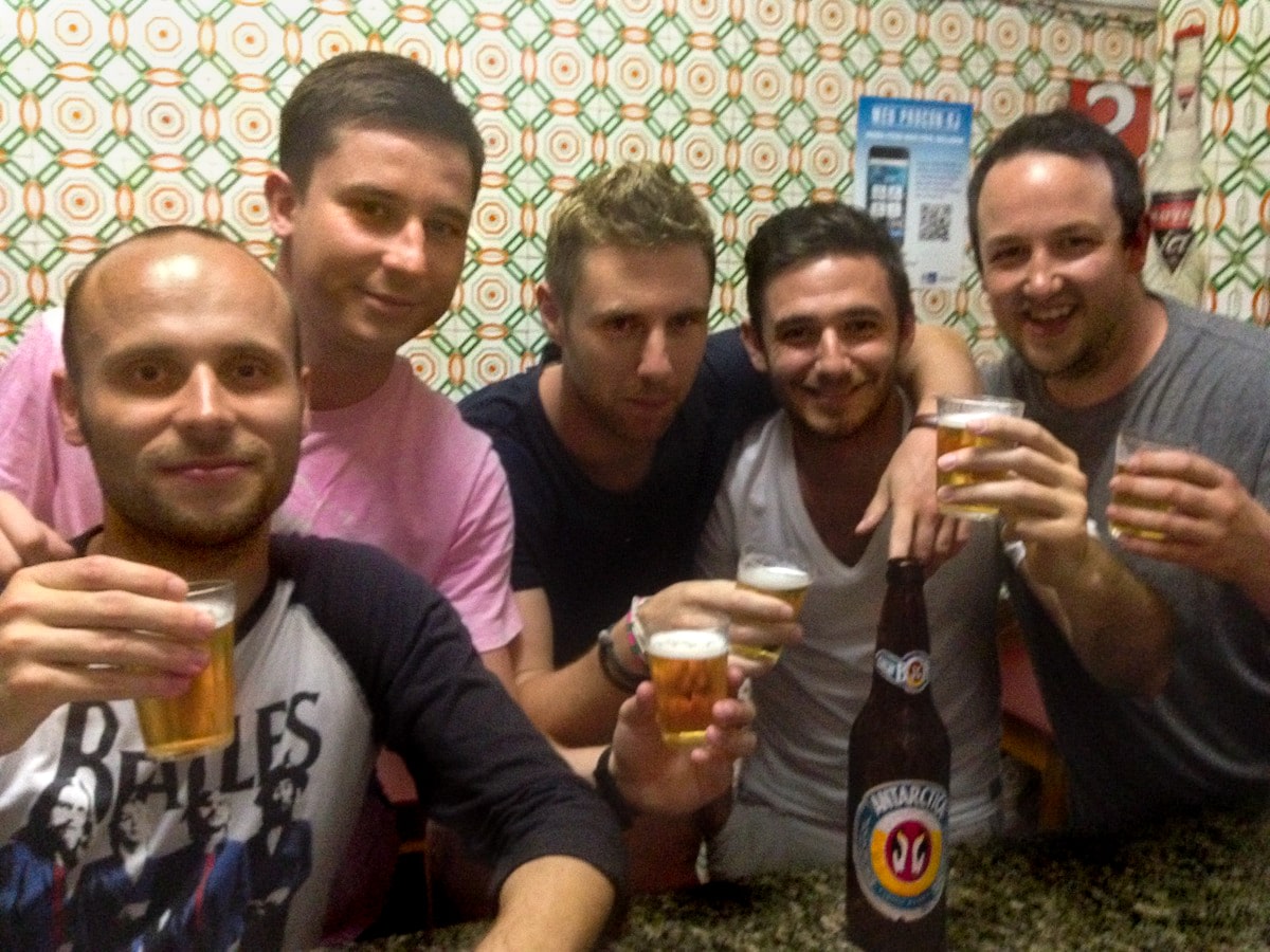 A group of men drink and pose at a grimy bar.