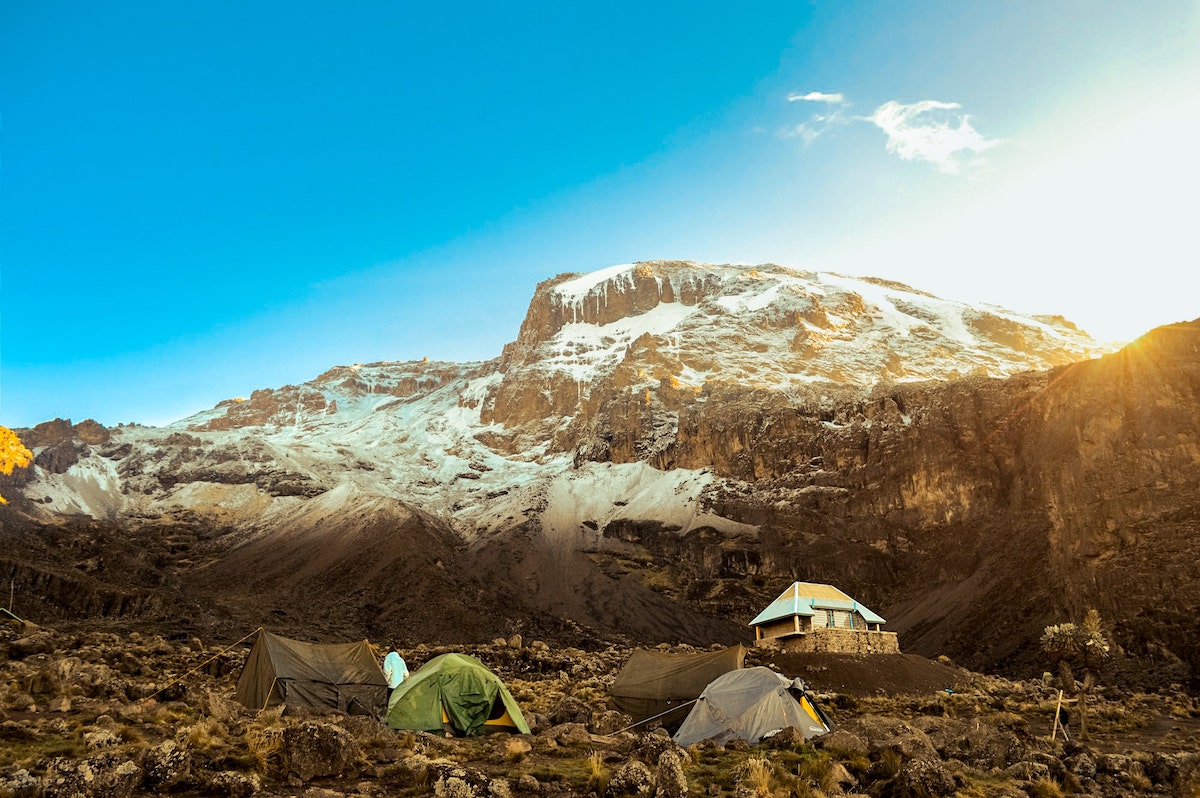An icy mountain with tents and a hut during the day on Mount Kilimanjaro, Tanzania.