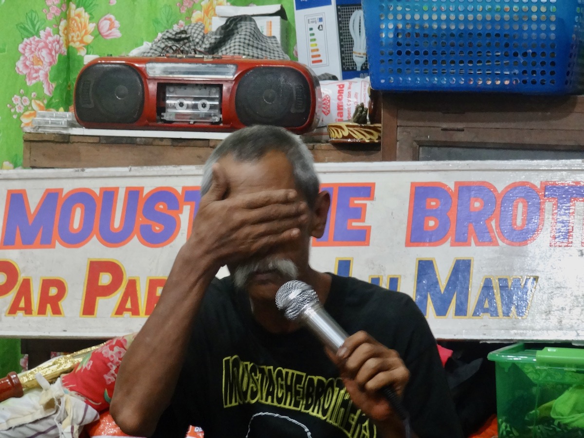 Lu Maw, member of The Moustache Brothers comedy act holds his hands over his eyes during a show in Mandalay, Myanmar