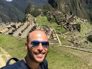 A male tourist smiles at Macchu Picchu in Peru