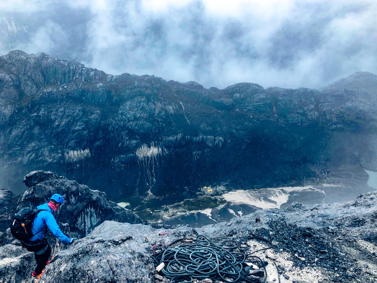 A male climber on Puncay Jaya with a beautiful misty landscape in the background