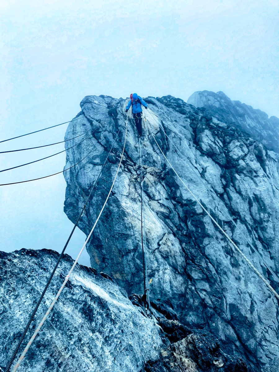 A climber braces himself for the rope bridge on Puncak Jaya