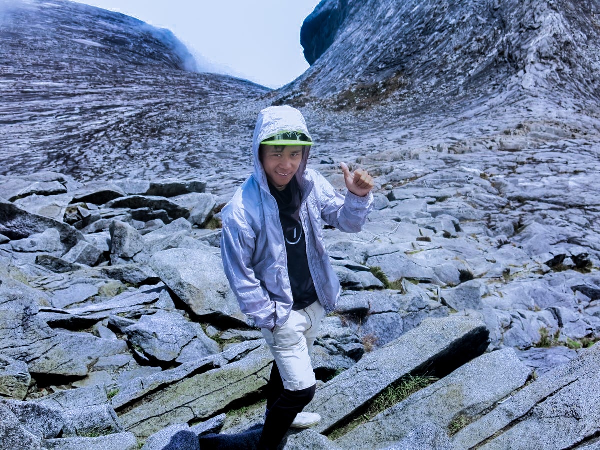 A male mountain guide smiles with a thumb up on Mount Kinabalu, Malaysian Borneo.
