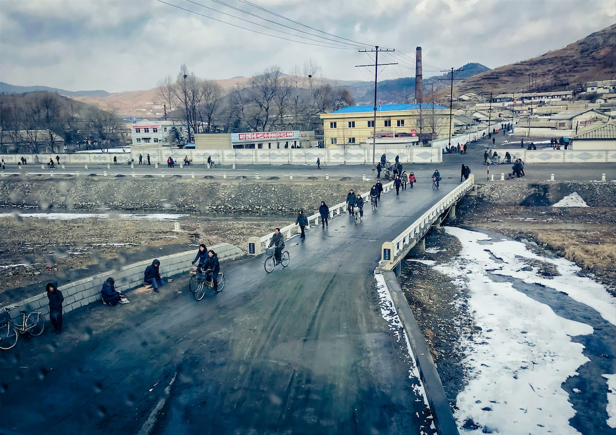 People walking and cycling on a murky day in rural North Korea