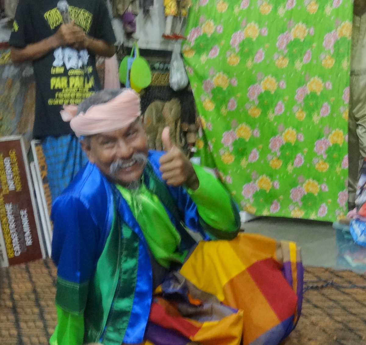 Par-Par Lay the brains behind Myanmar's comedy act, 'The Moustache Brothers' smiles and raises a thumb up while sitting on the floor