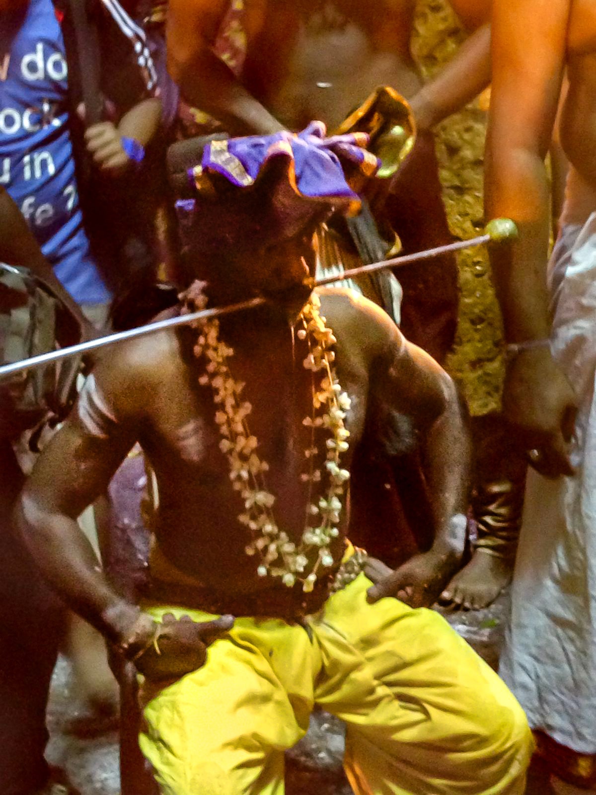 A Hindu man in yellow trousers sits with a metal pole through his cheeks at the Thaipusam Festival in Batu Caves, just outside of Malaysia's capital city.