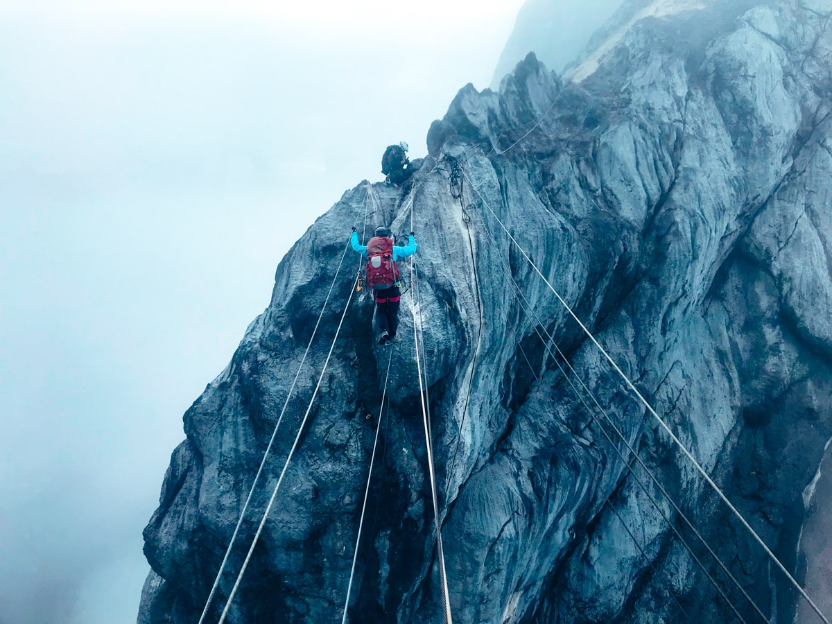 A climber walks the Rope Bridge on Carstenz Pyramid