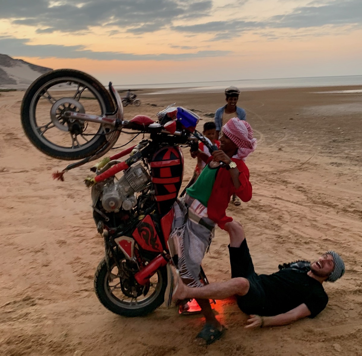 A tourist laughs as he falls off a young man's motorbike in Socotra Island, Yemen