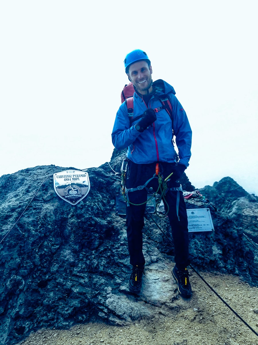 A man smiles as he reaches the summit of Puncak Jaya