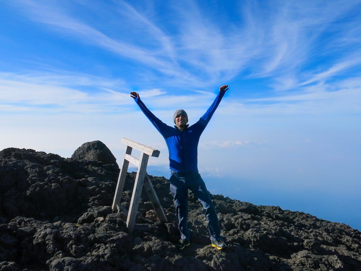 Man with arms raised high as he summits Mount Fuji in Japan.