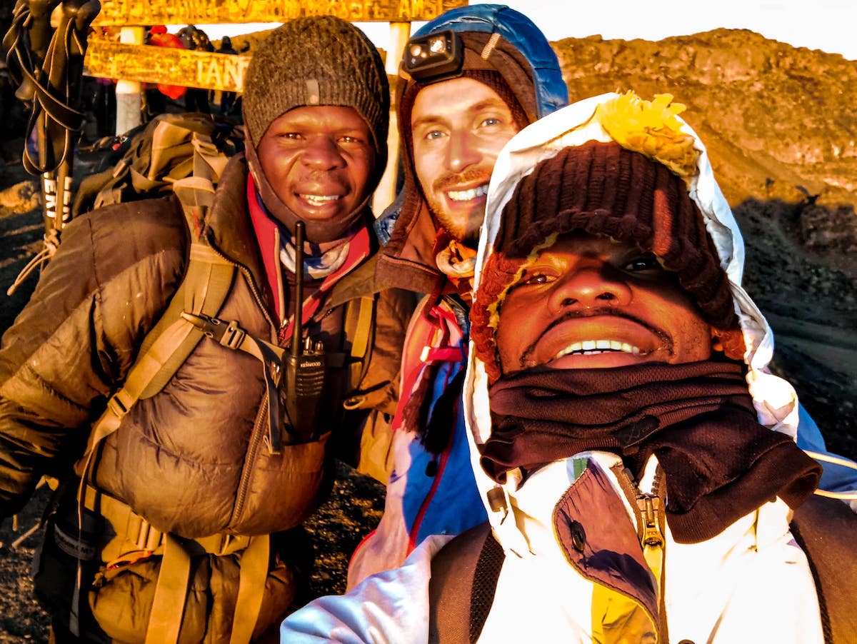 Three men smile with mountain gear on.