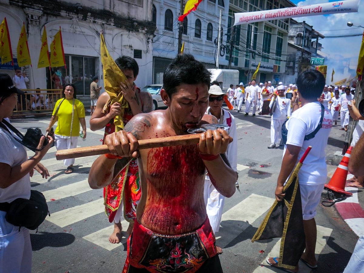 A man licks an axe, as his body is pouring with blood during the Thailand Vegetarian Festival in Phuket. 