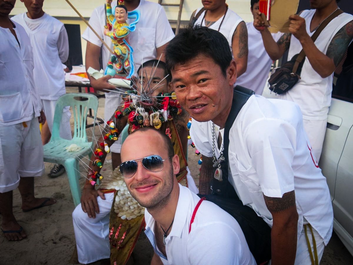 Tourist smiling with Peranakan locals at The Thailand vegetarian festival in Phuket.