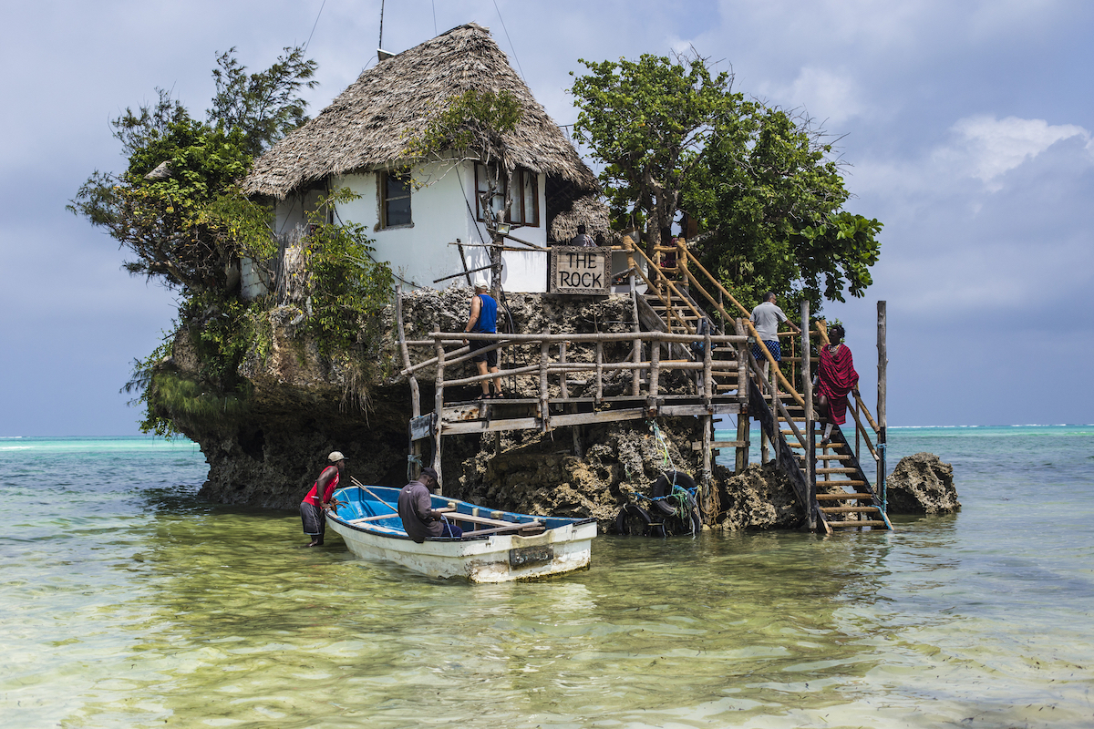 Men sit on a boat outside a cafe situated on a small island in Zanzibar