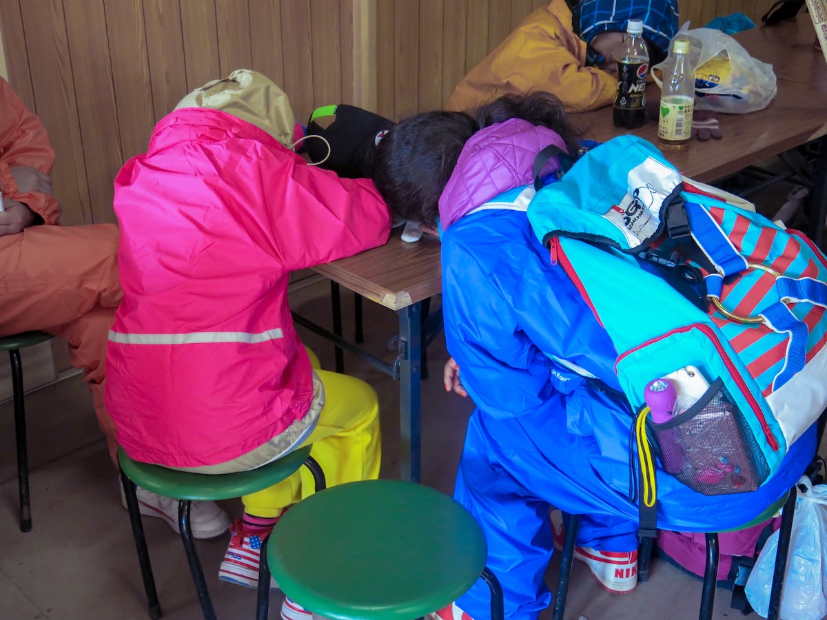 Two female climbers sleeping with their heads on a table.