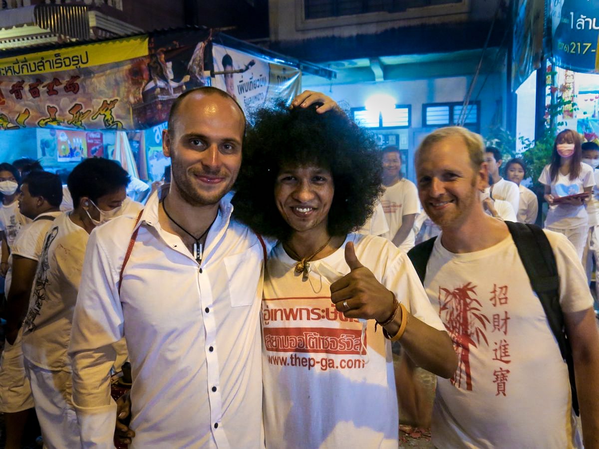 Three men in white, one guy smiles with an afro haircut. 