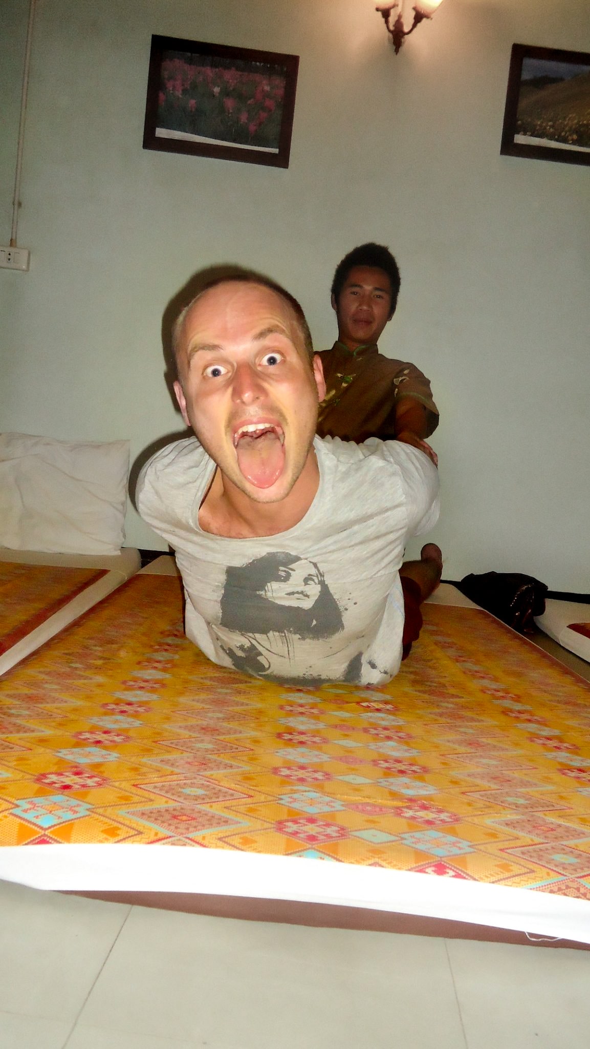 A man pulls a silly face while receiving a firm Thai massage in Bangkok, Thailand. 