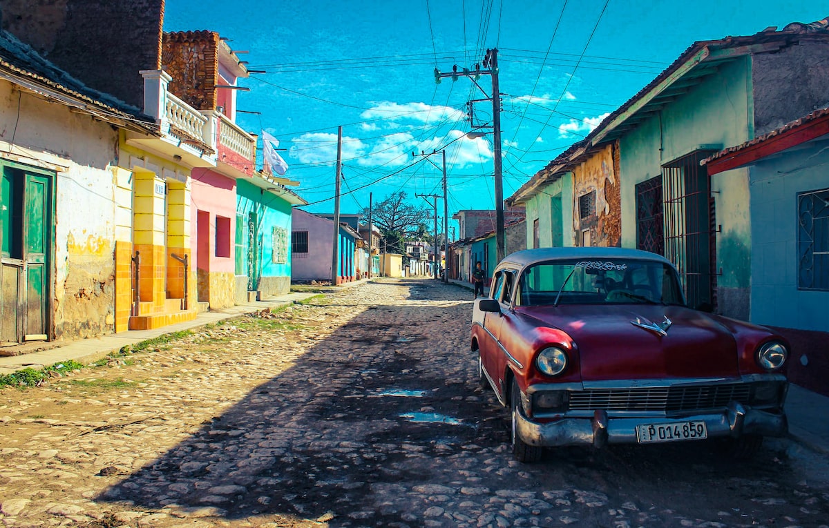 A red classic car in the colourful cobble stone streets of Trinidad, Cuba.