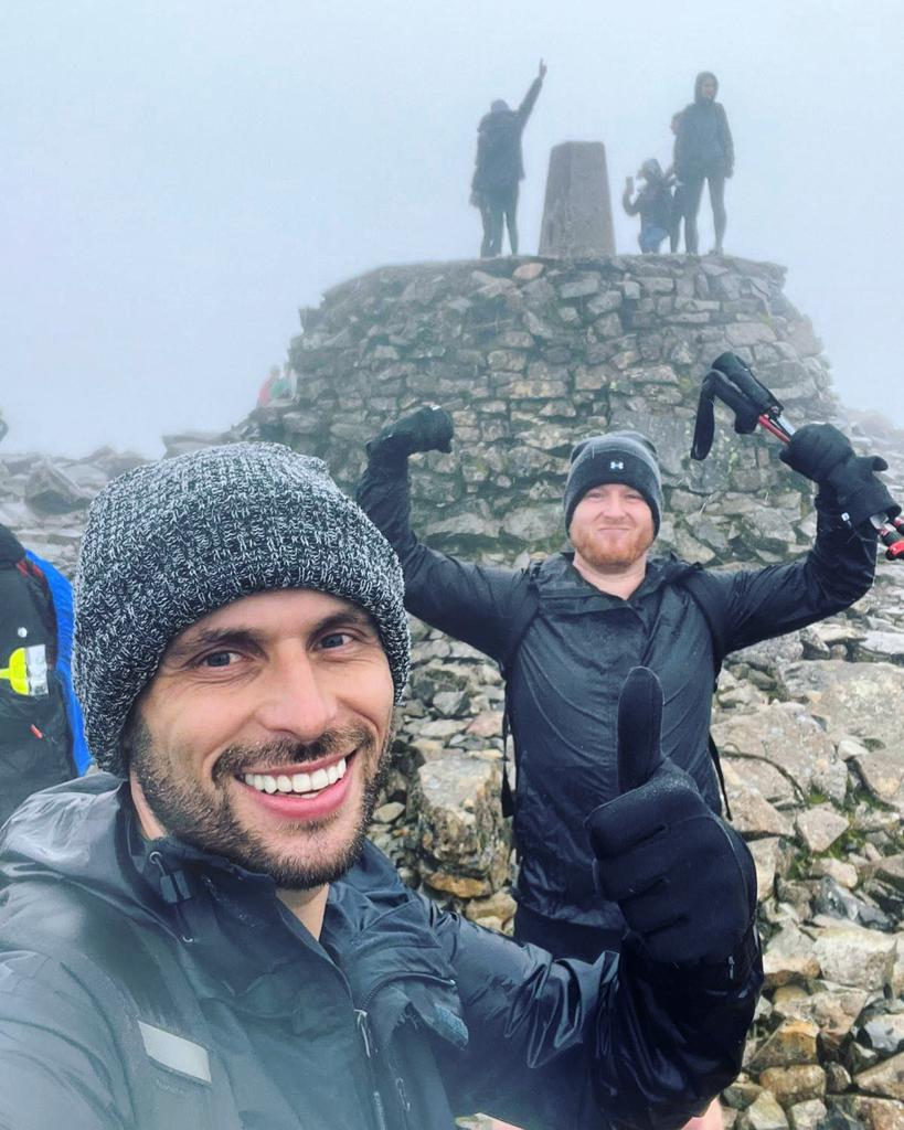 Hikers smile at the top of a mountain during the National Peaks in 24 hours challenge in the United Kingdom