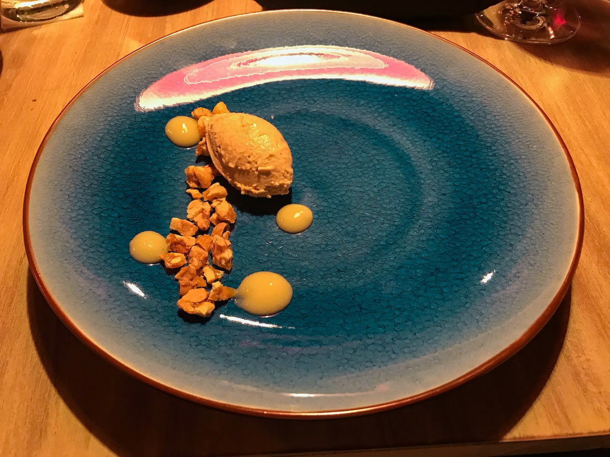 A small scoop of ice cream on a blue plate with honeycomb pieces.