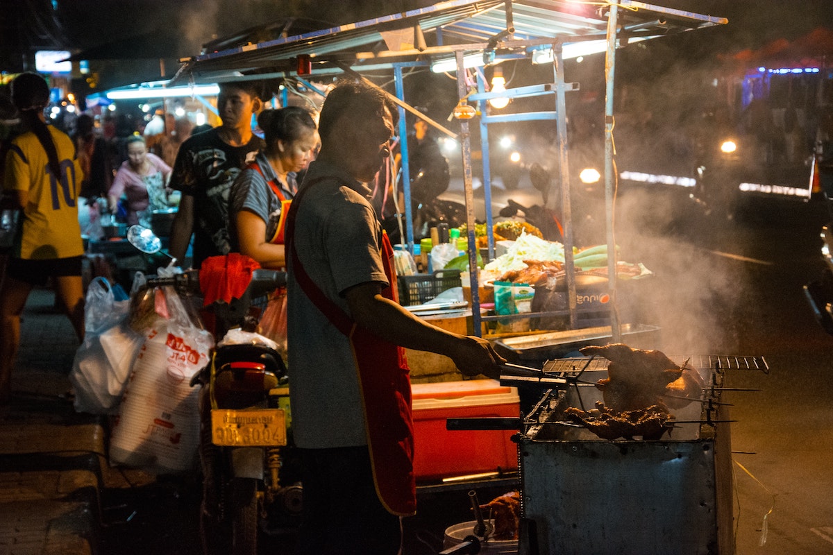 A man fries chicken in a street market in Vientiane, Laos