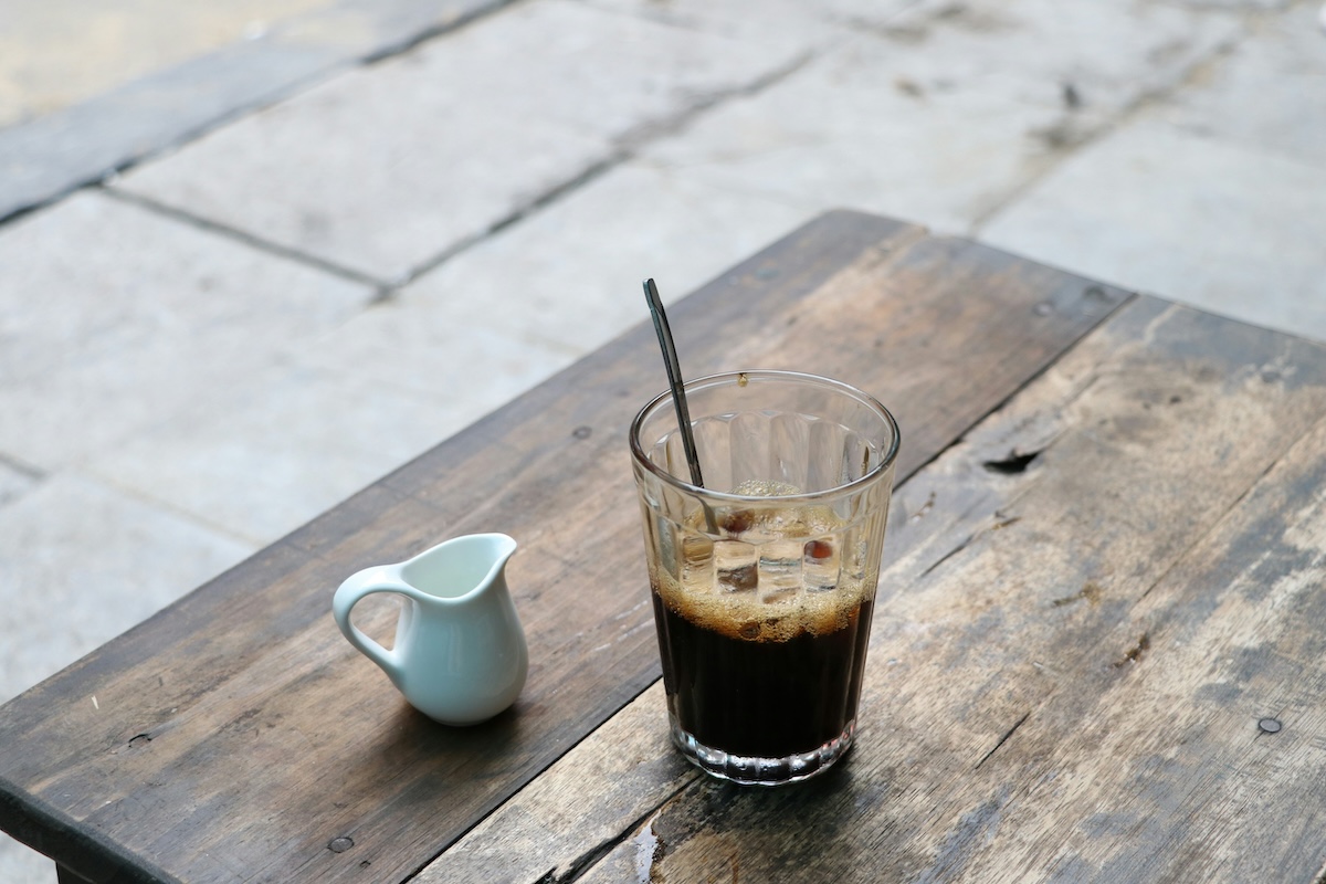 Vietnamese iced coffee on a wooden table with a small white jug