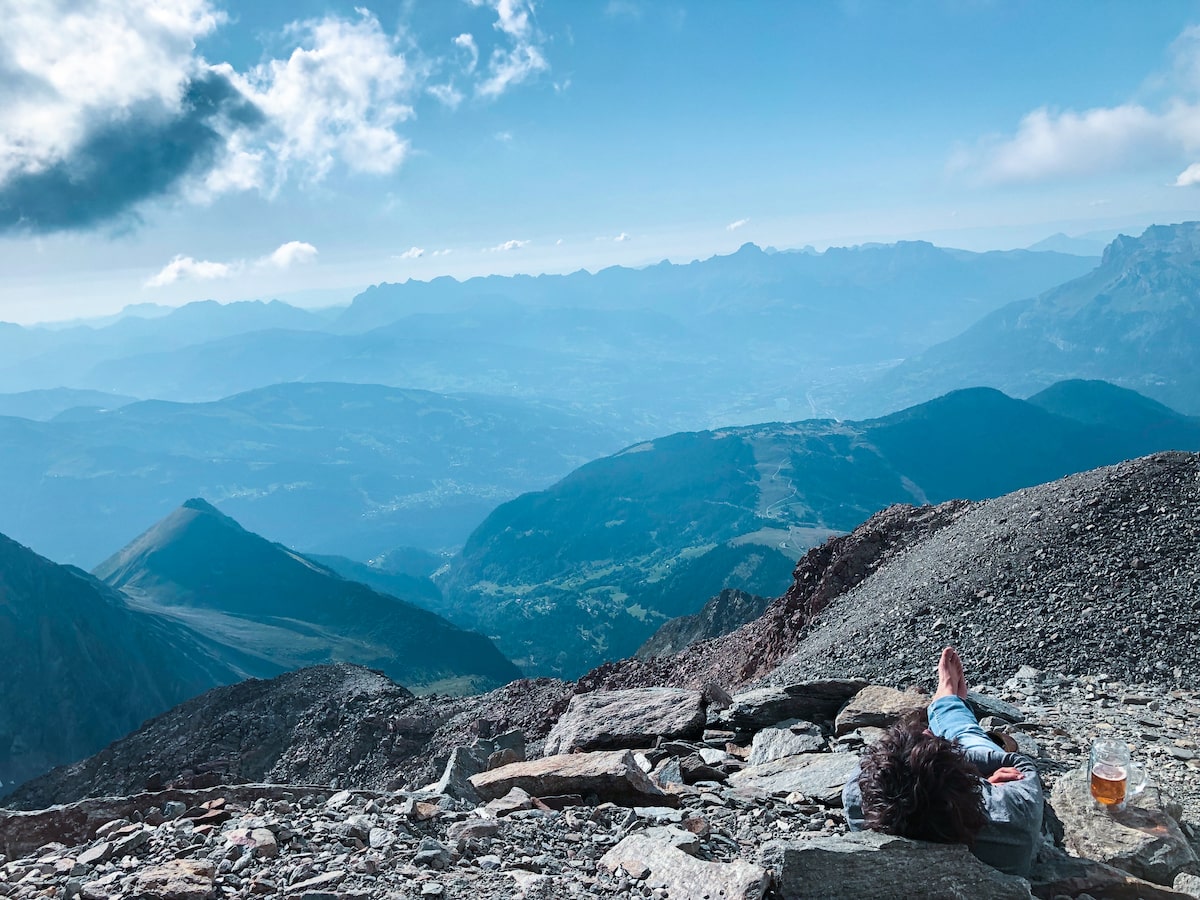 A man sits with a beer, overlooking a mountainous region in Mont Blanc, France.