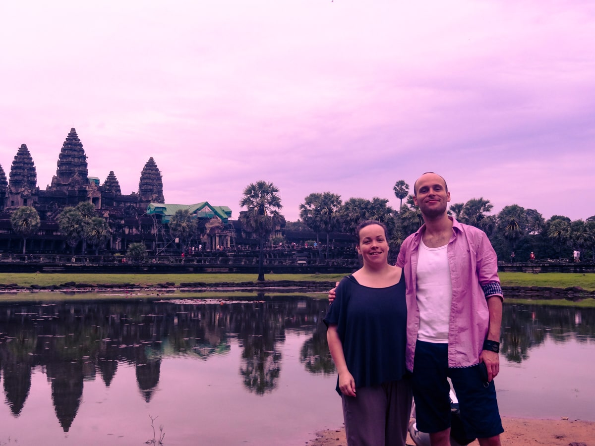 A man and a woman pose at sunrise while visiting the Angkor Wat Temple in Cambodia
