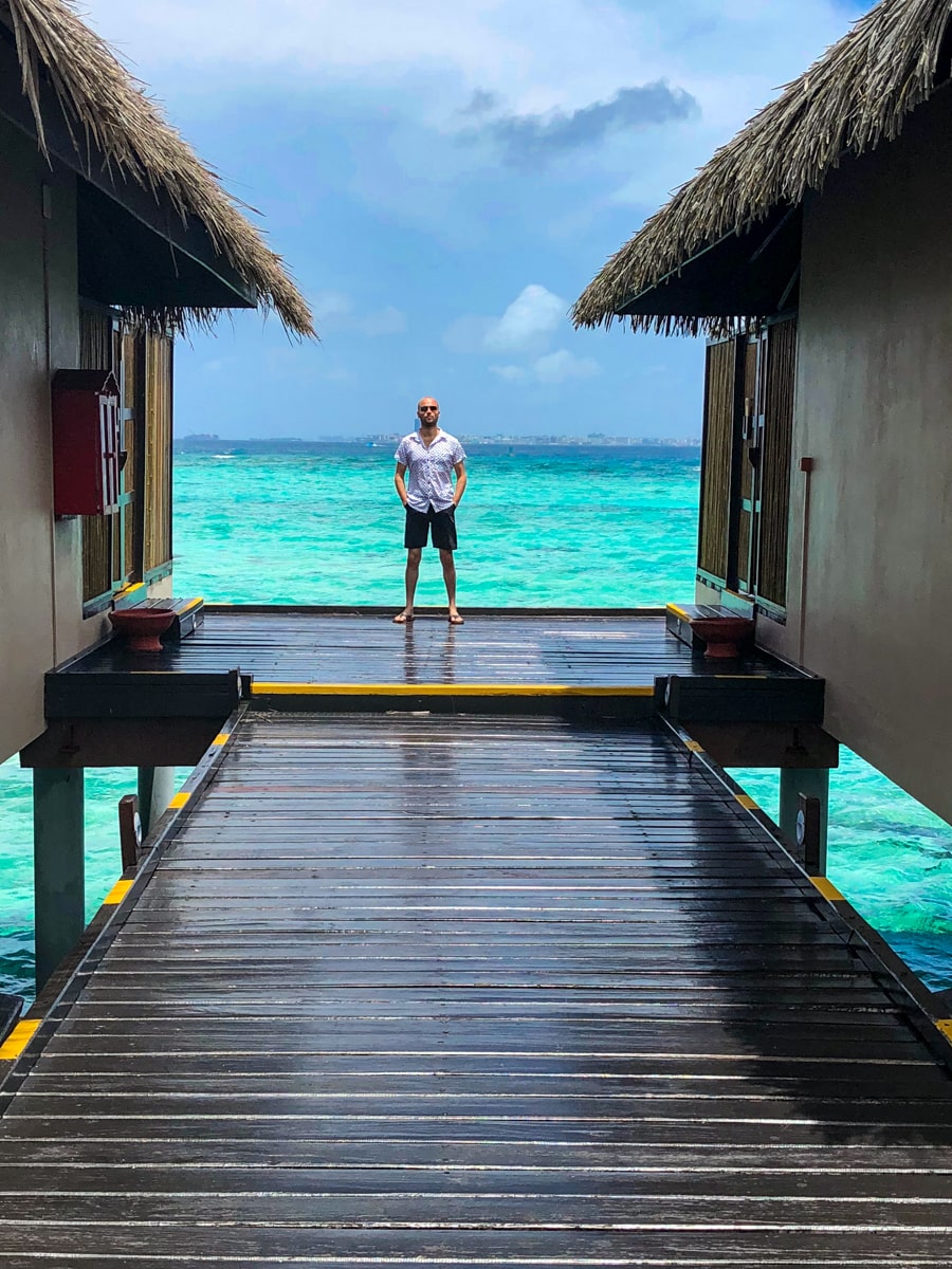 A male tourist poses between two water villas in the beautiful Maldives