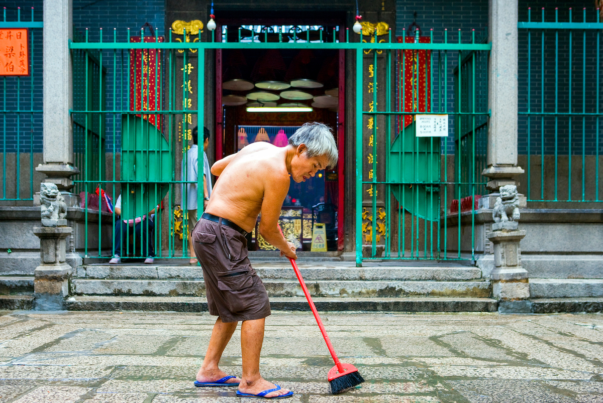 An old man sweeps the entrance of the Tin Hau Temple in the Yau Ma Tei quarter