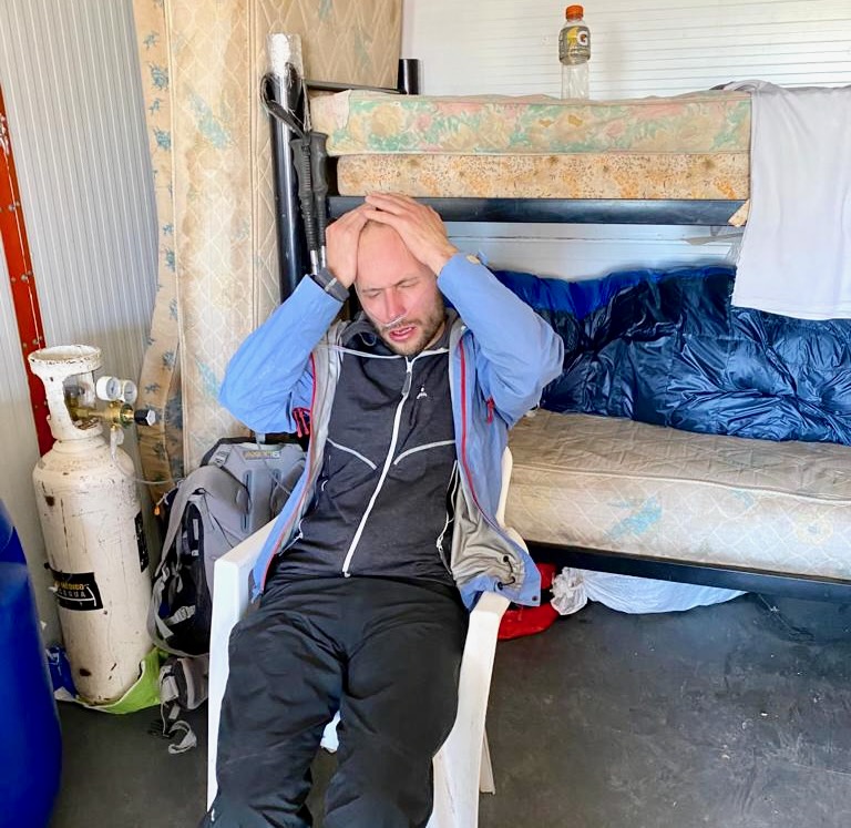 A man holds his head in agony as he receives oxygen from a tank after a mountain accident