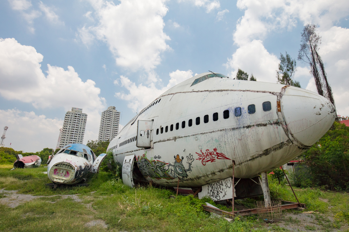 Remains of a wrecked and graffitied Boeing 747 and two McDonnell Douglas MD-80s in a field in Bangkok, Thailand
