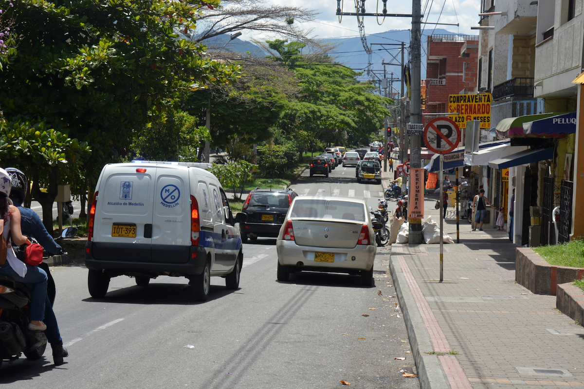 Cars driving down the road with trees on the sidewalk in Belen, Medellin. 