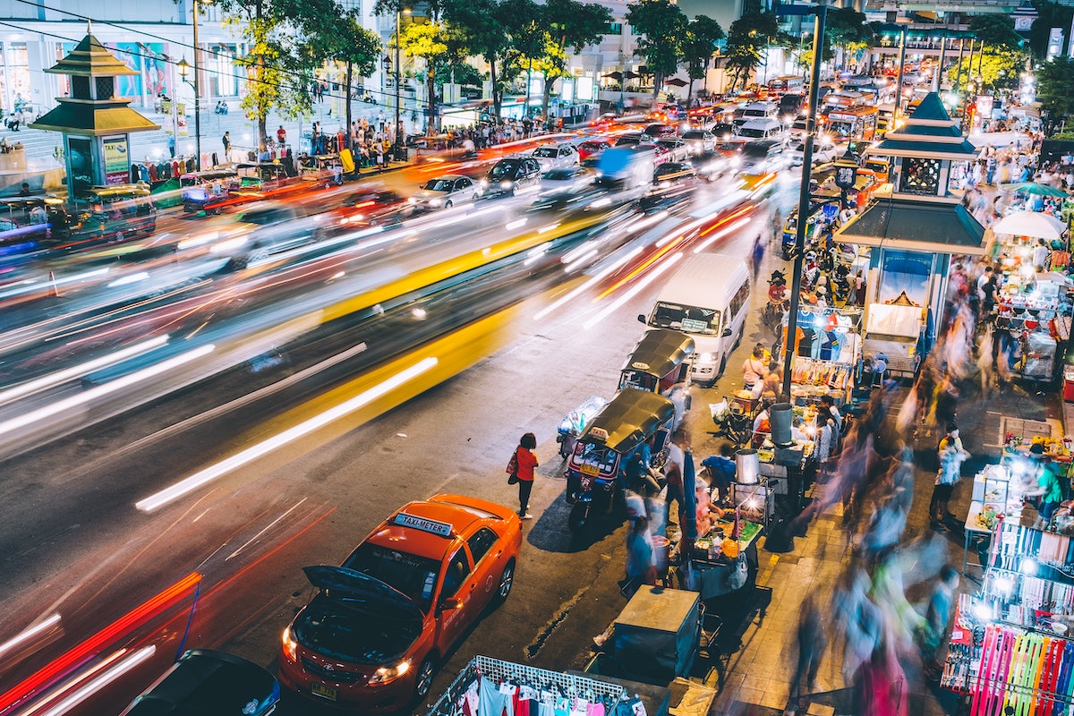 Busy traffic and sidewalks full of people in Bangkok city