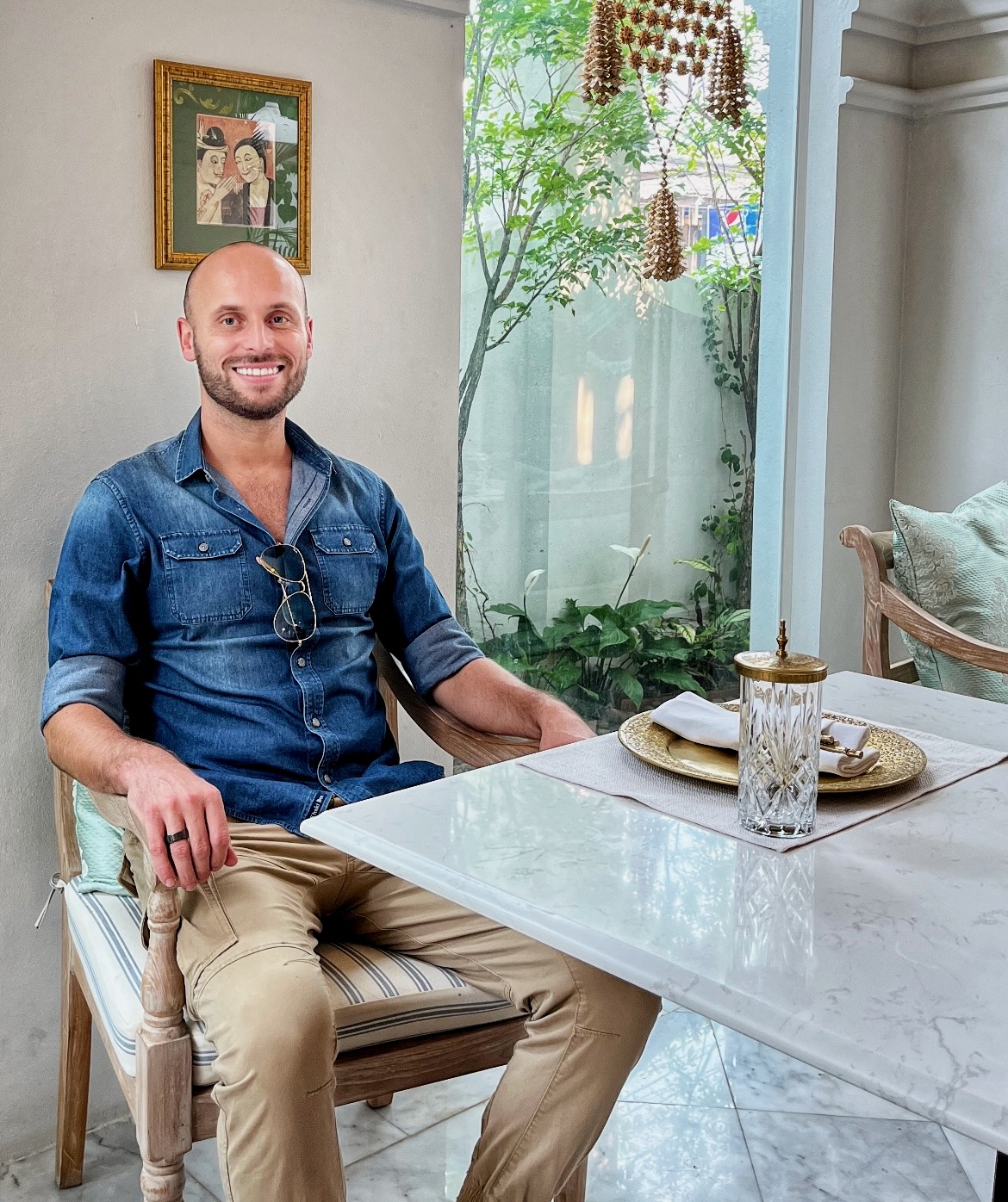 A man in a blue shirt smiles at a table in a cafe in Chiang Mai, Thailand