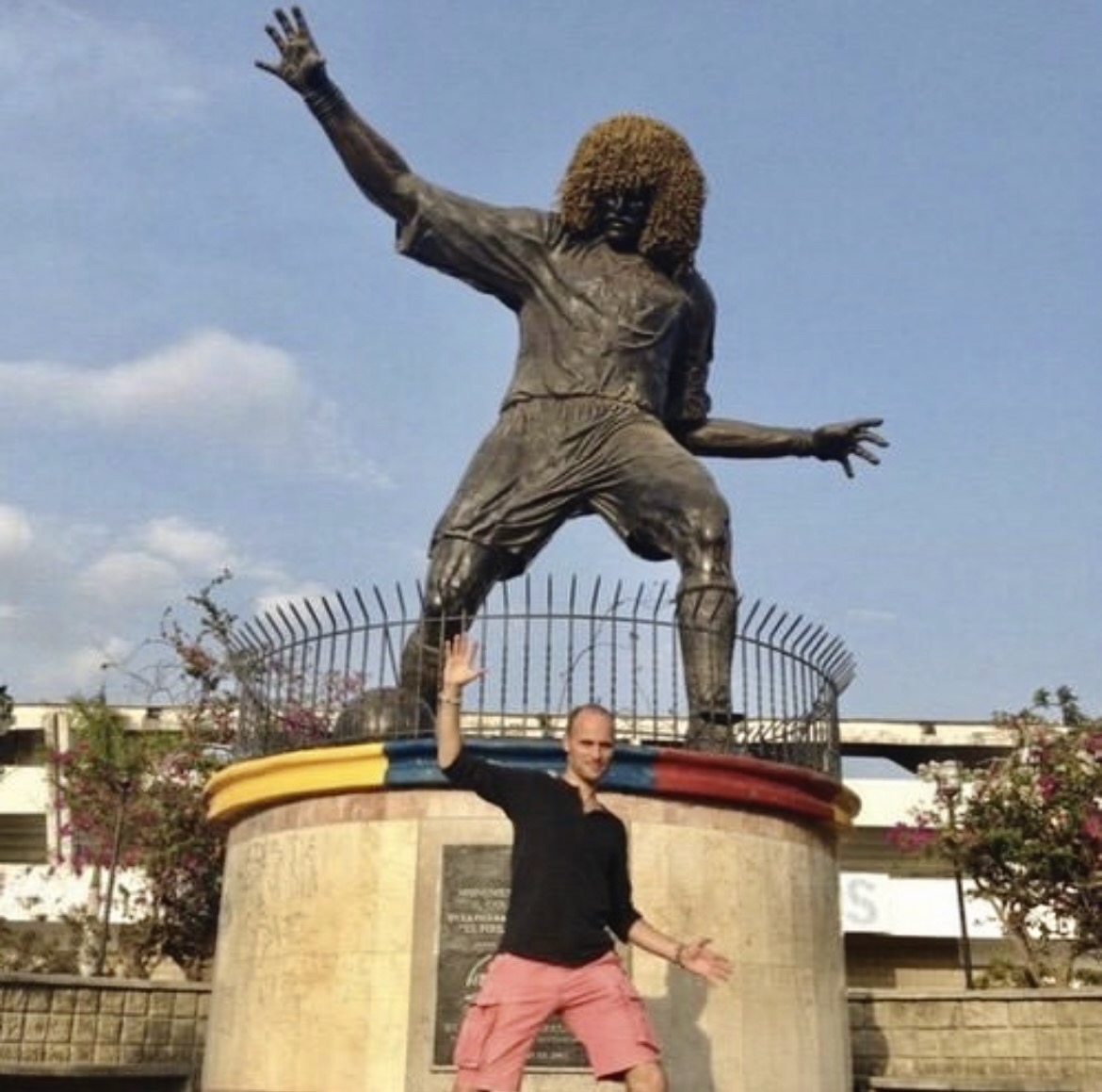 A male tourist recreates the pose of a statue of Carlos Valderrama.
