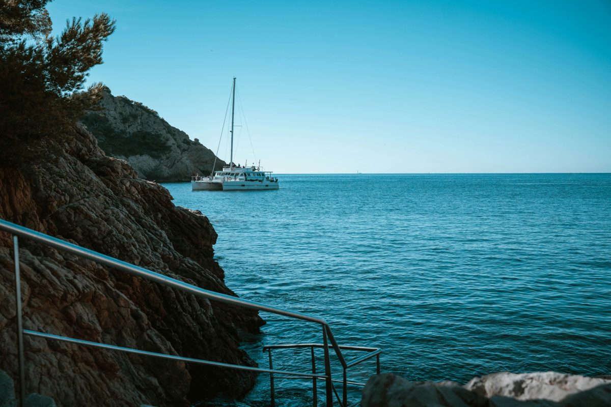 Catamaran sailing near rocky cliffside