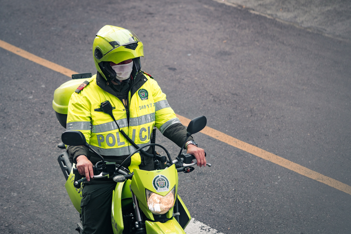 A Colombian policeman on a motorbike wearing a mask. 