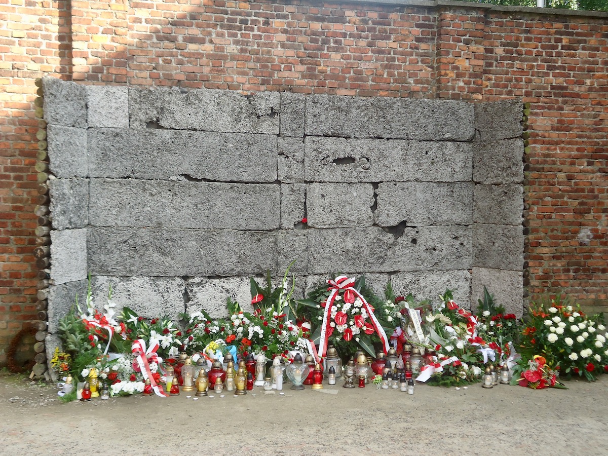 The infamous Death Wall of Auschwitz with reefs and flowers laid down