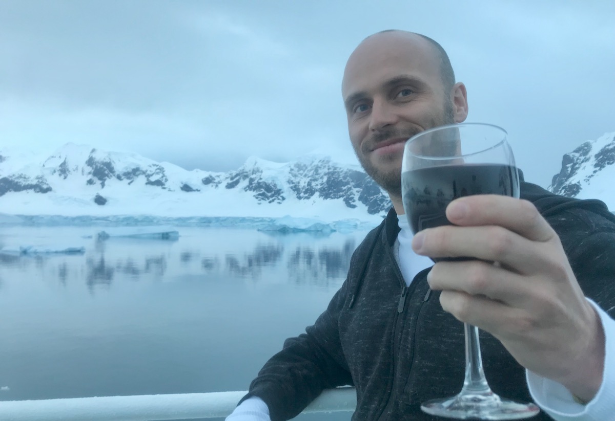 Drinking wine on an Antarctic cruise ship with a beautiful snowy landscape reflecting off the water