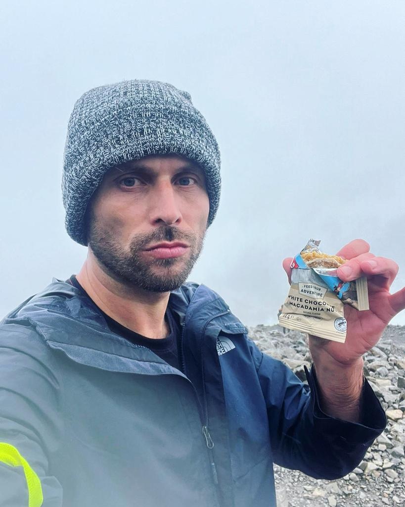 Hiker eating a Clif bar wearing a hat