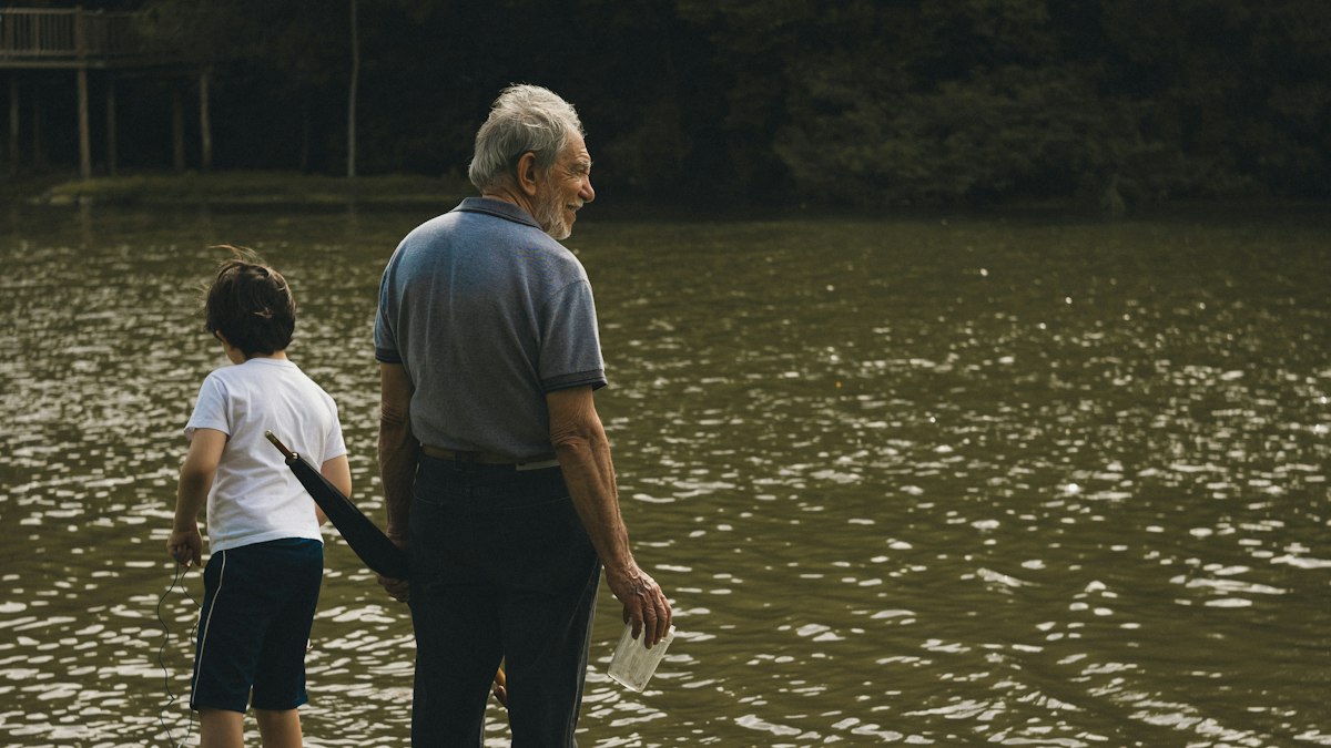 Why Post Falls, Idaho Is Perfect for Multi-Generational Family Vacations | grandfather and grandson by a lake Grandfather and grandson standing by a lake on a family vacation