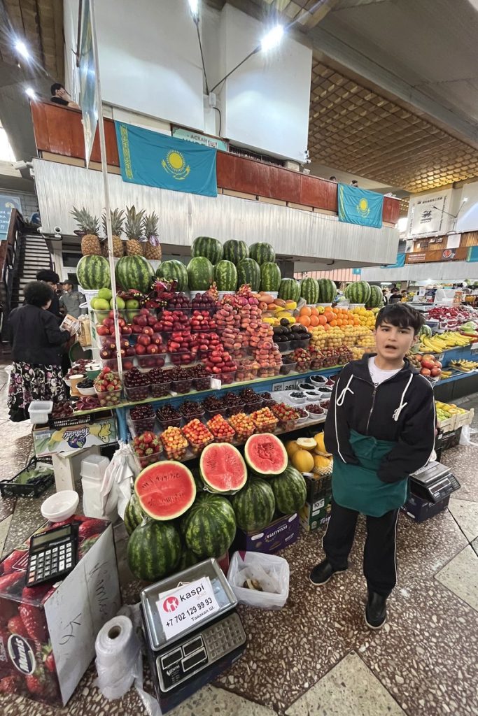 Stacked watermelons and fresh fruit at a stall in Almaty's Green Bazaar