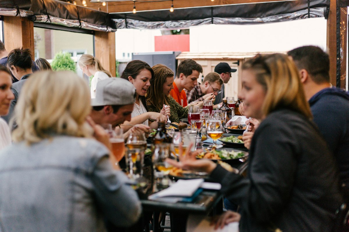 The Space Between: Why Group Travel Fails When Your Accommodation Does | group of friends sharing dinner together Group of friends sitting around a table sharing a meal together