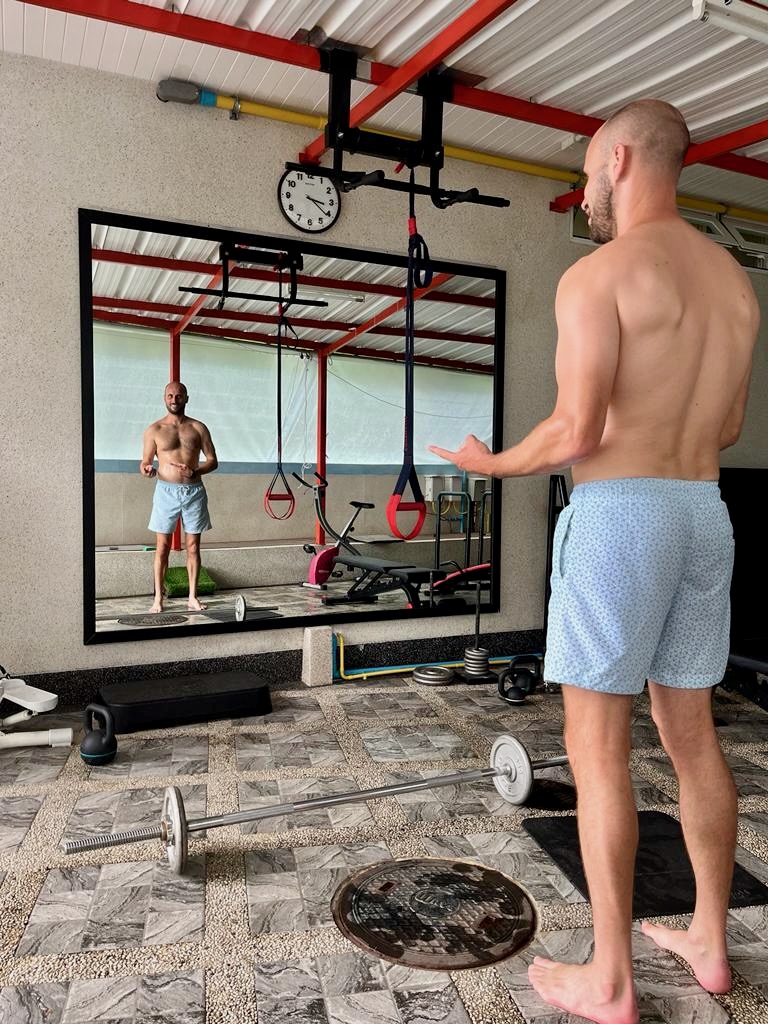 Man looks at himself shirtless in the mirror 