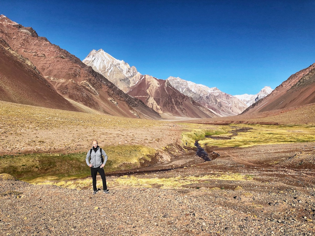 A mountain climbing standing in front of the view on Mount Aconcagua while hiking up to Camp Confluencia