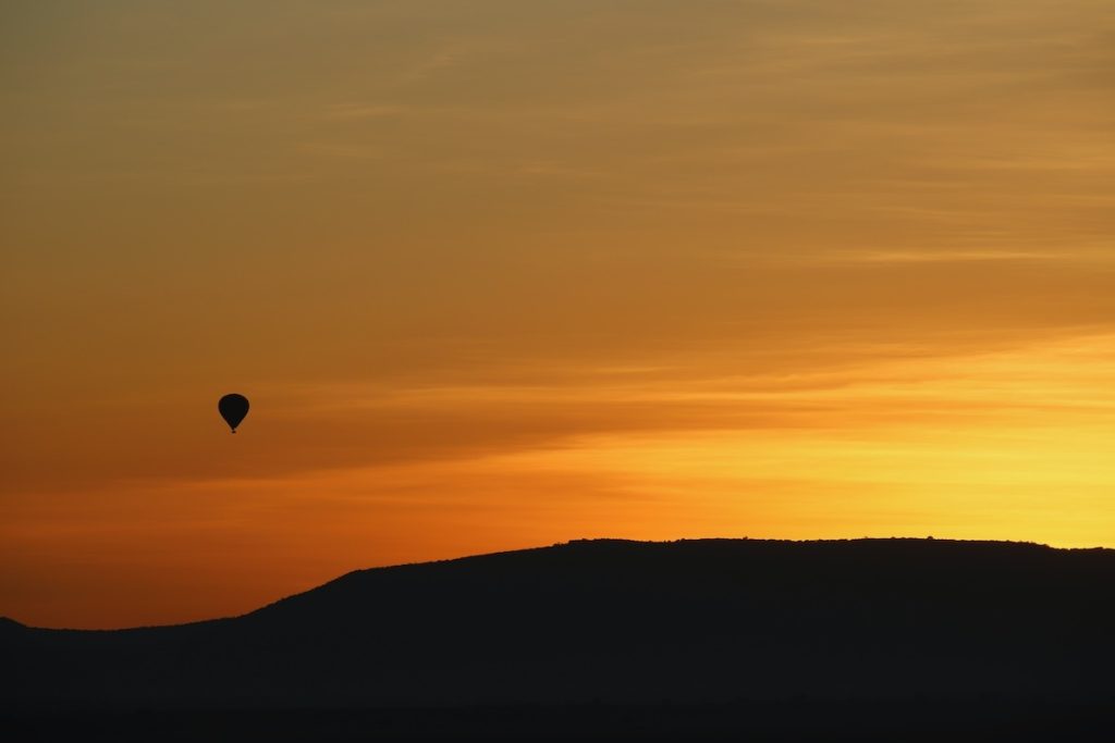 Hot air ballon flies through the sky at sunset