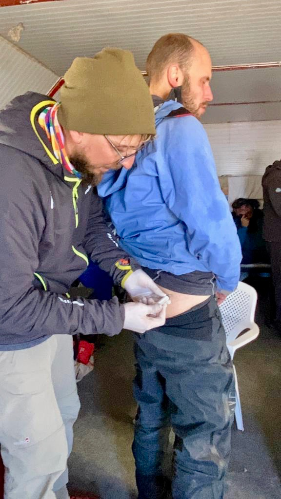 A climber on Aconcagua grimaces with altitude sickness as he receives a steroid injection into his buttocks during an Aconcagua expedition in Argentina